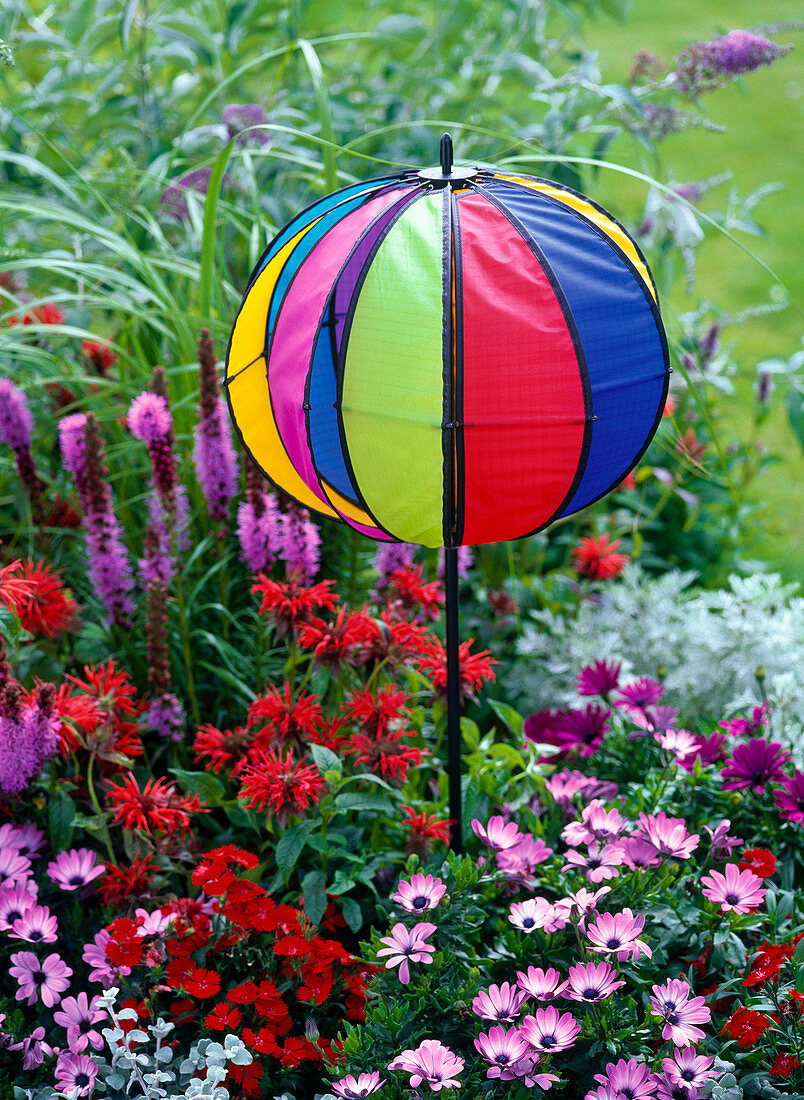 Ball-shaped colourful wind chimes in a flower bed