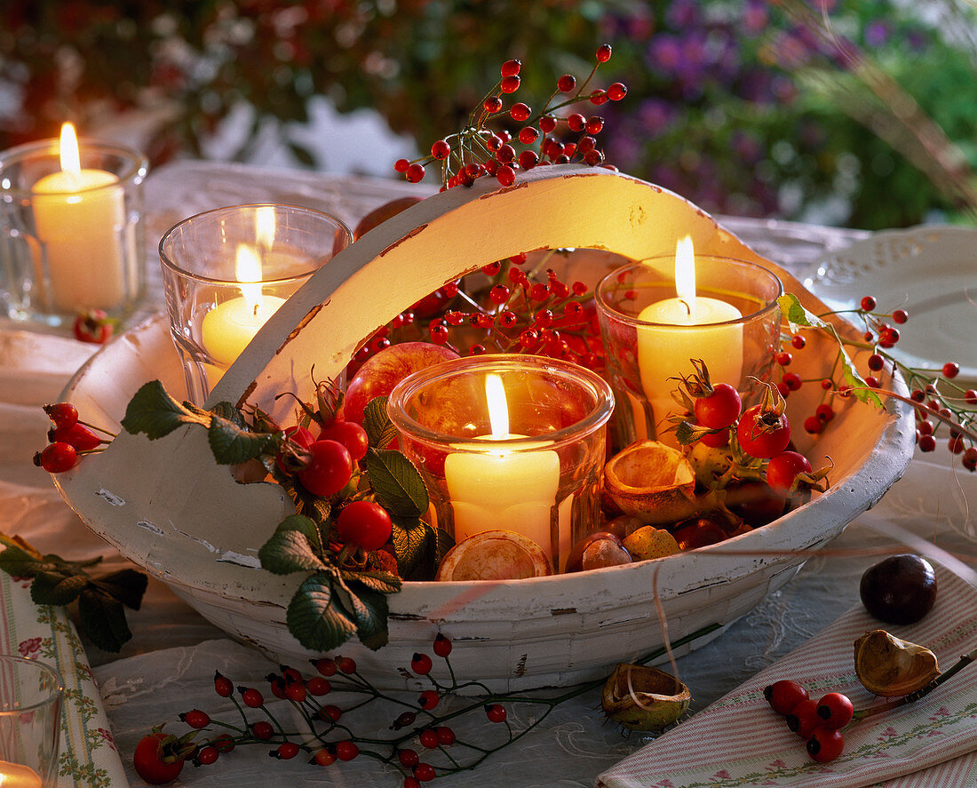 Lanterns in clay basket with handle decorated with rose hips and Aesculus