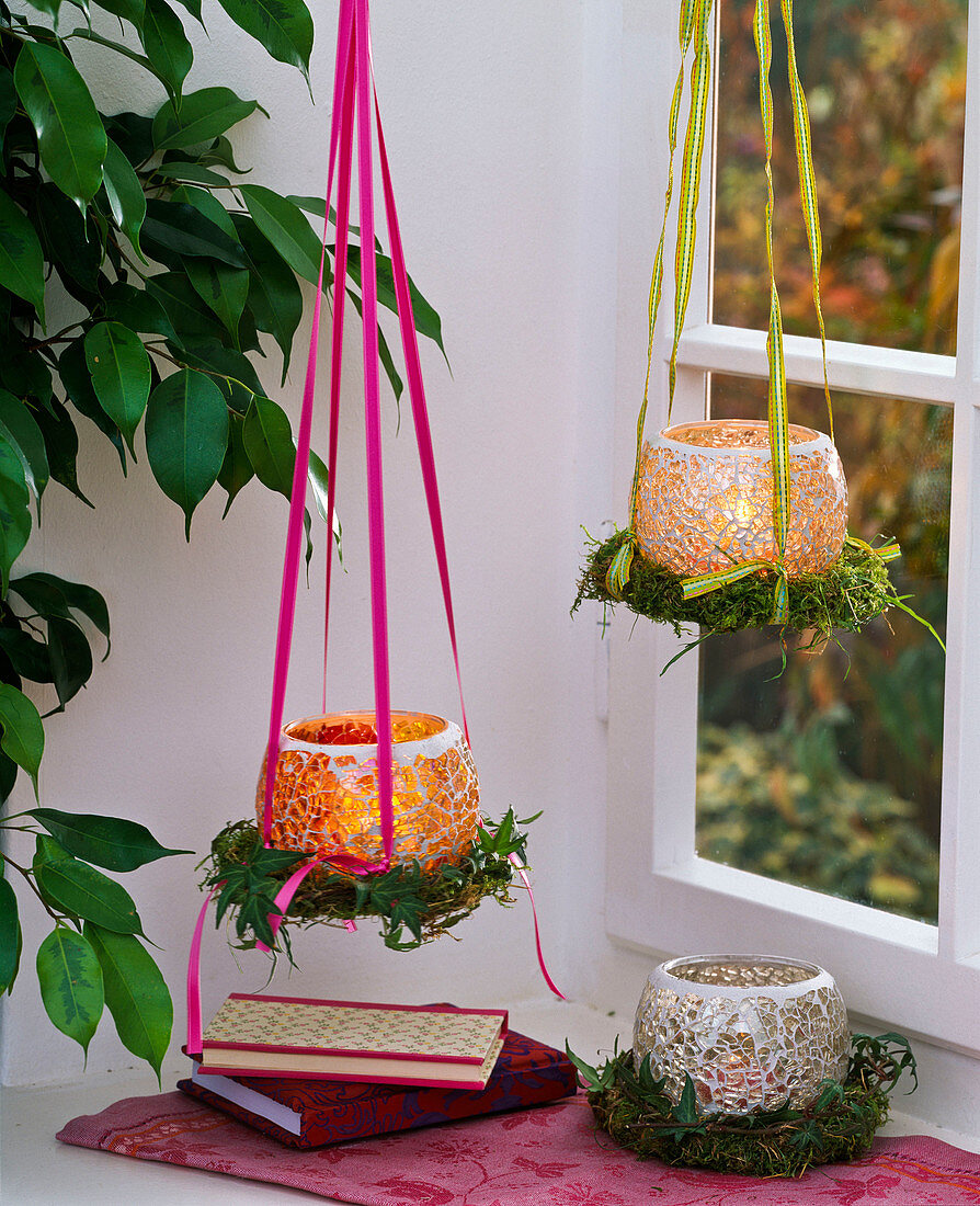 Lanterns made of mosaic glass hanging on small wreaths of moss in the window