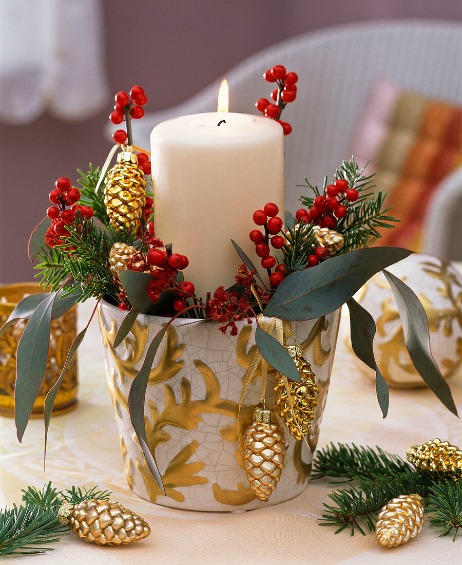 White candle in a white-golden planter, holly