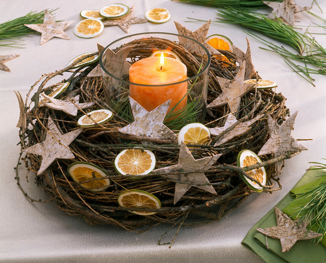 Lantern with orange candle in a wreath of Larix (larch twigs)