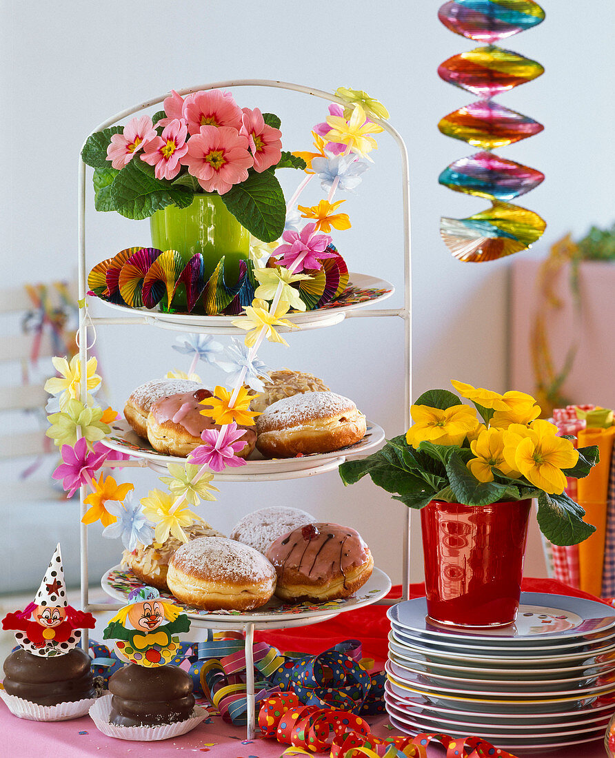 Carnival table decoration with Primula (primroses), etagere with doughnuts