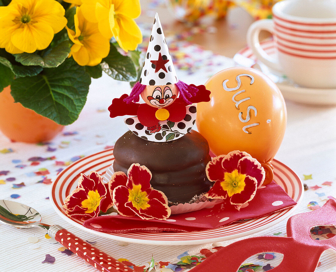 Carnival table decoration with Primula (primroses), doughnuts, balloon