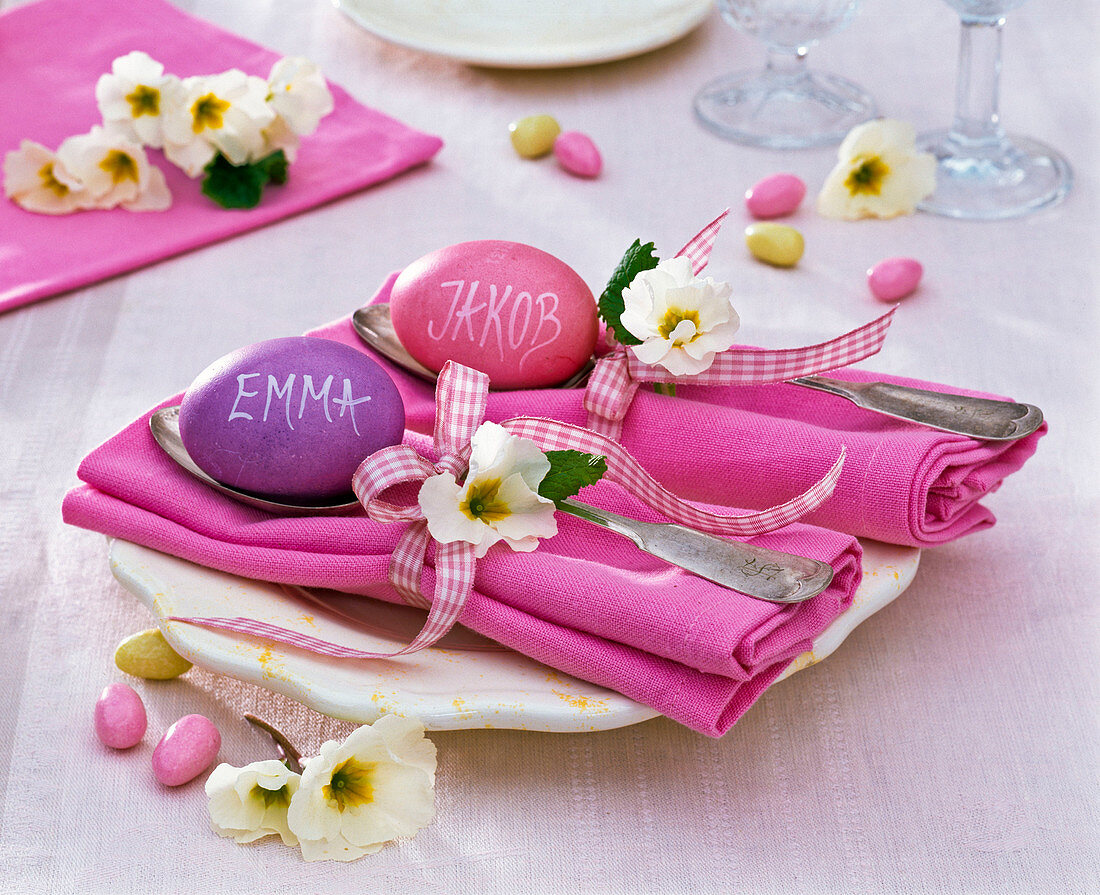 Tischdekoration mit Primula (Primeln) auf rosa gefalteten Servietten