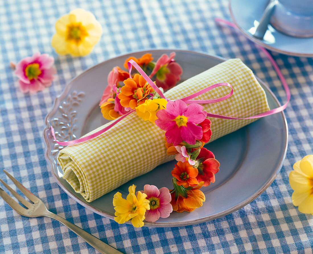 Necklace of primula on checkered rolled napkin