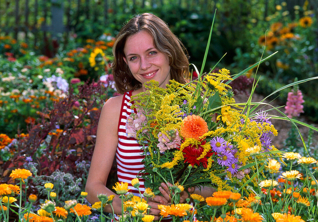 Junge Frau pflückt Blumenstrauß in Bauerngarten