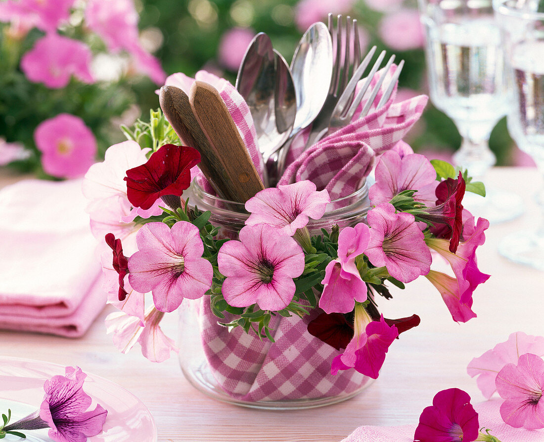 Wreath made of petunia around glass with napkin and cutlery