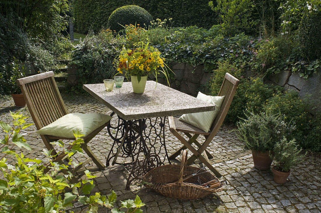 Paved terrace in front of an overgrown dry stone wall