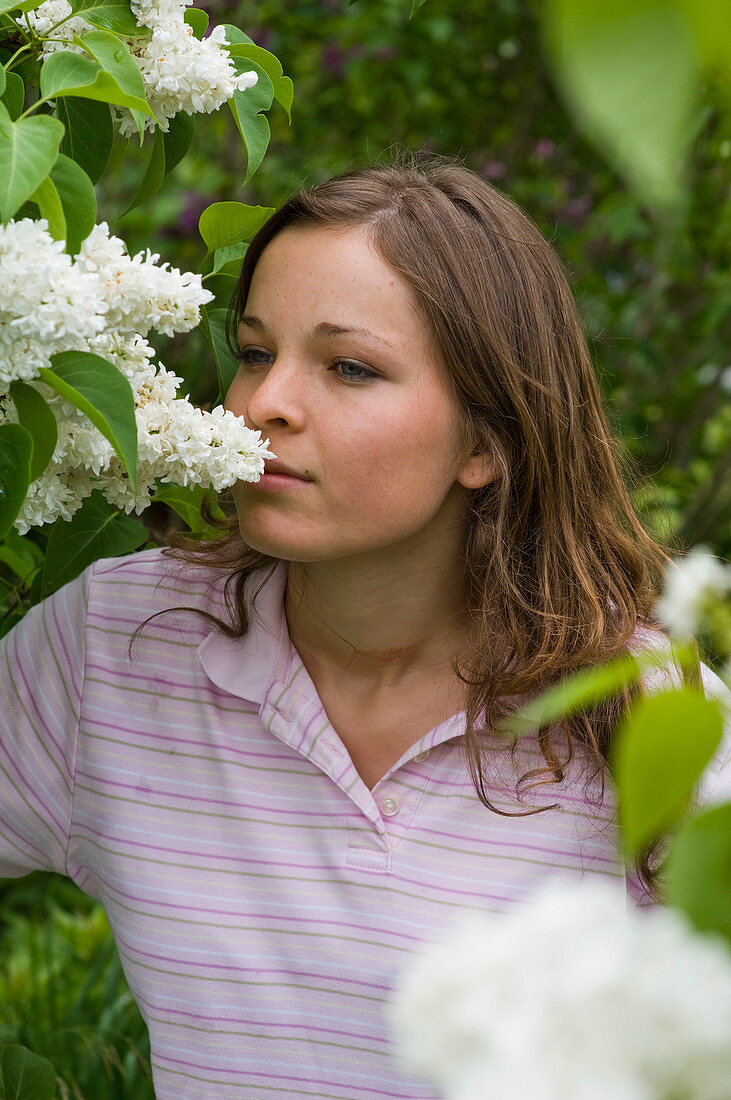 Frau schnuppert an Syringa 'Mme Lemoine' (Flieder)