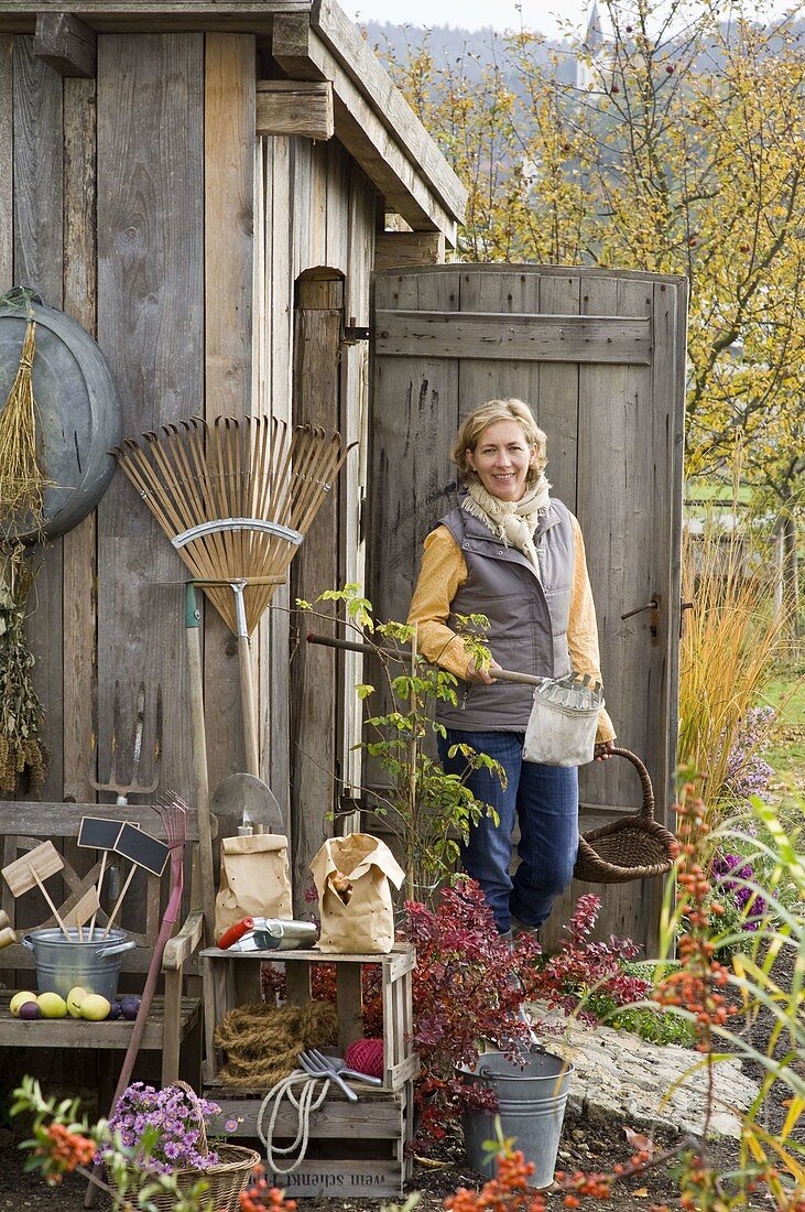Woman exiting garden tool shack with fruit picker and wicker basket