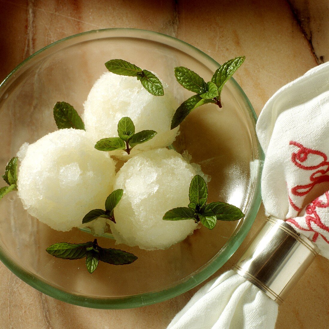 Drei Kugeln Champagnersorbet mit Minzeblättchen auf Teller