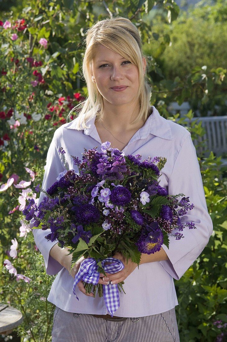 Young woman with bouquet of Callistephus (Summer Aster), Salvia horminium