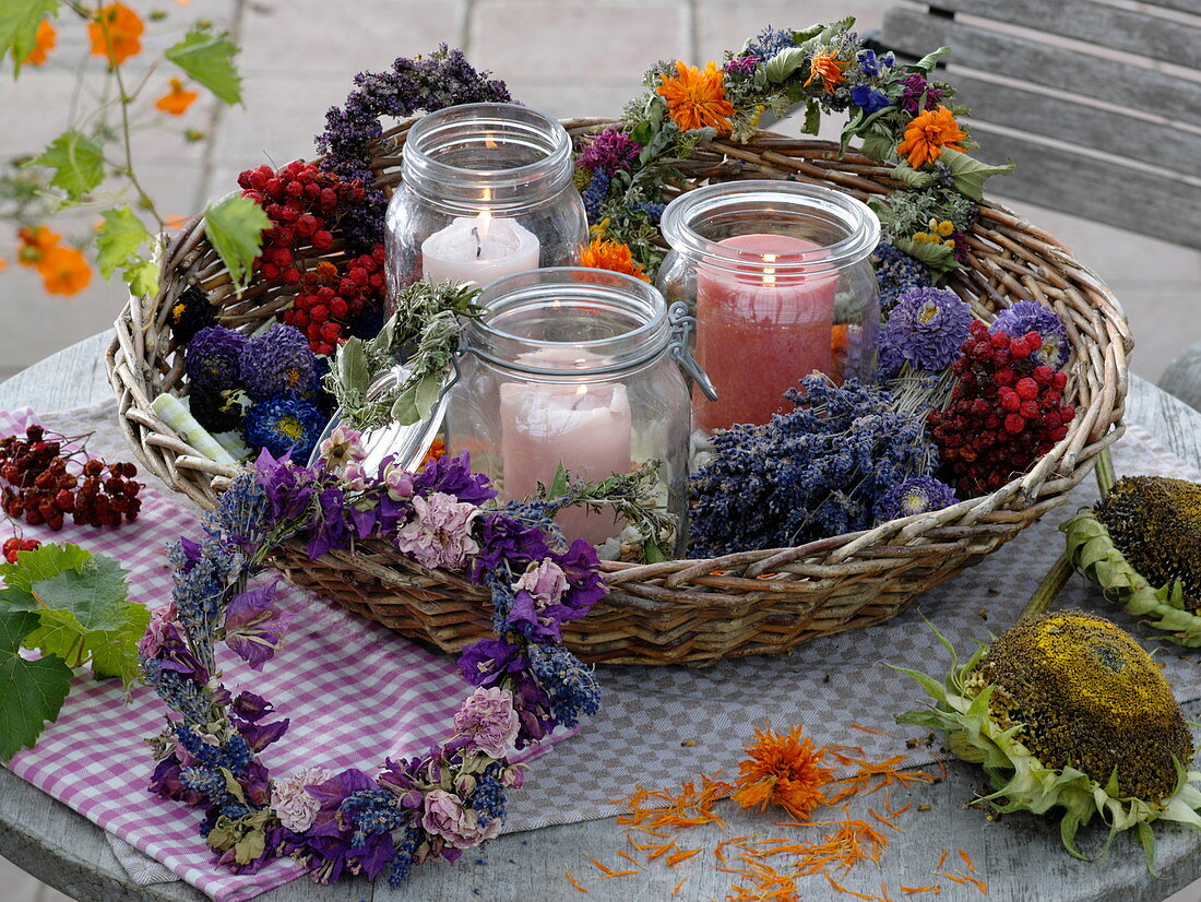 Windlichter in Korb mit getrockneten Kränzen, Beeren und Blüten