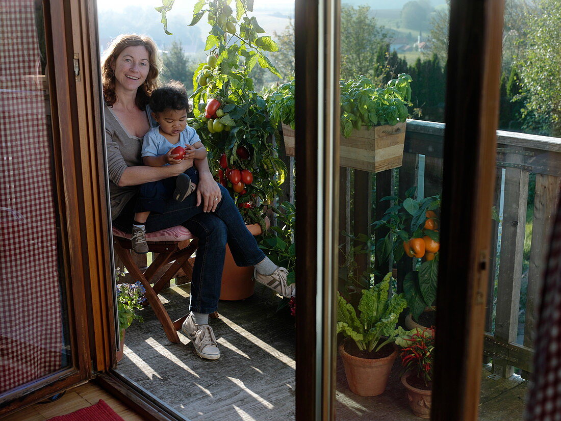 Little boy with tomato on mum's lap