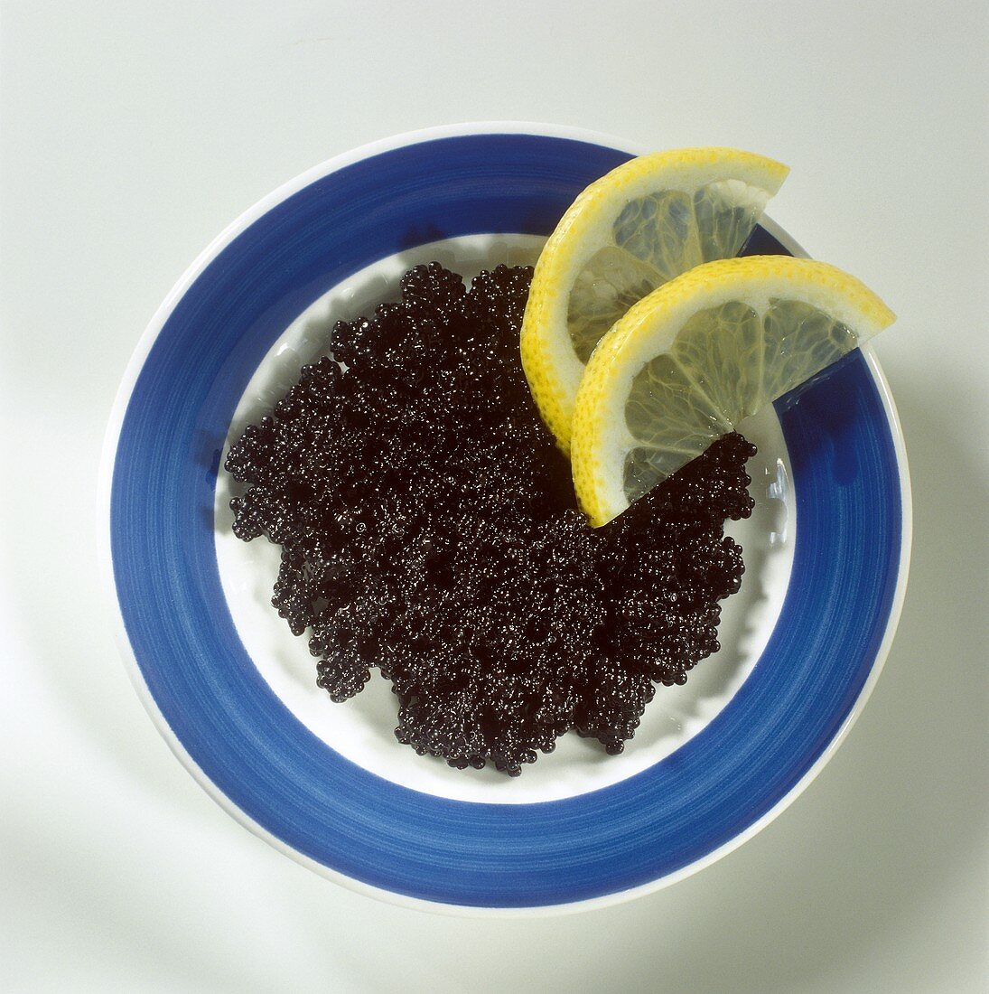 Schwarzer Kaviar auf Teller mit Zitronenschnitzen