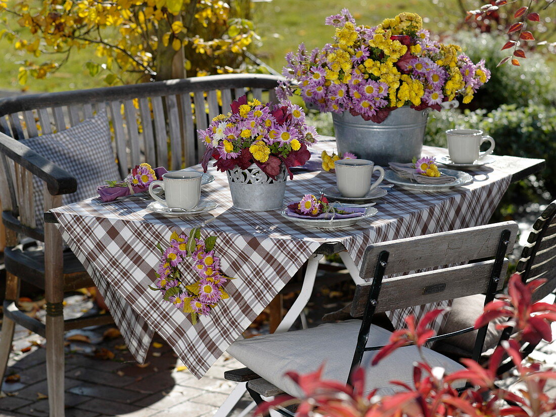 Herbstliche Tischdeko mit Herbstchrysanthemen und Heuchera-Blättern