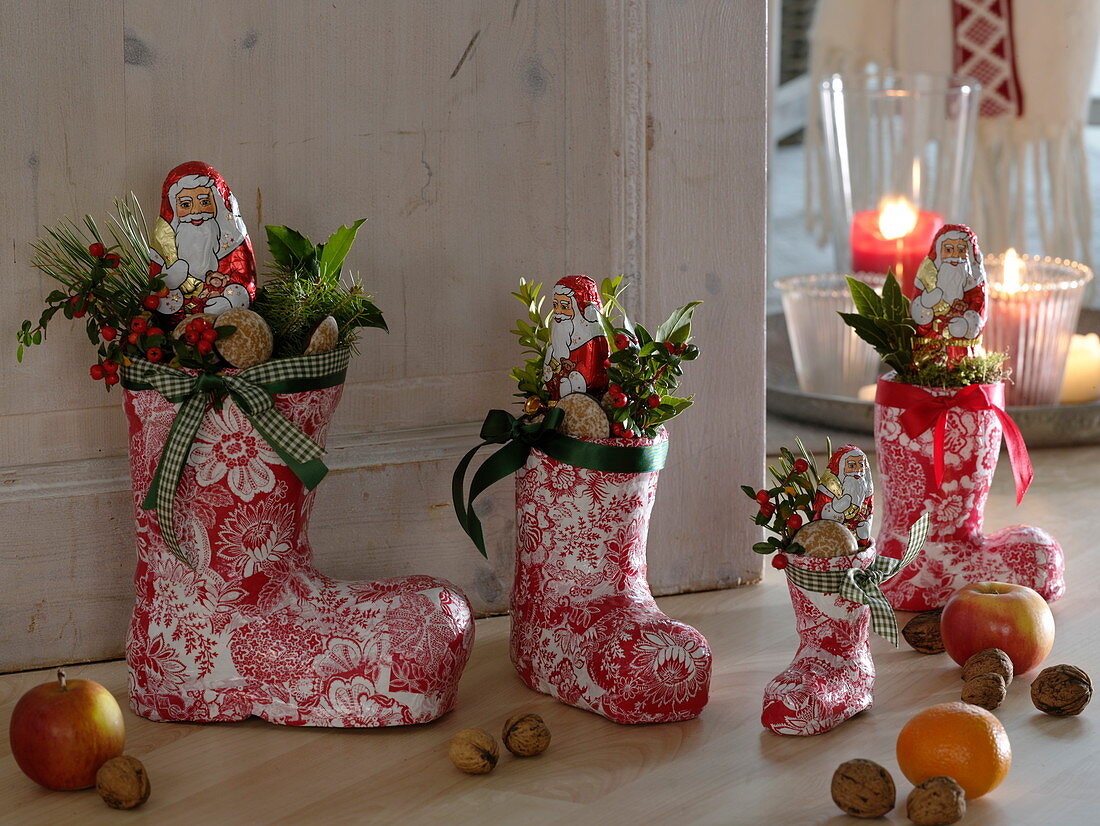 Red and white Santa boots made of papier-mâché in front of the door