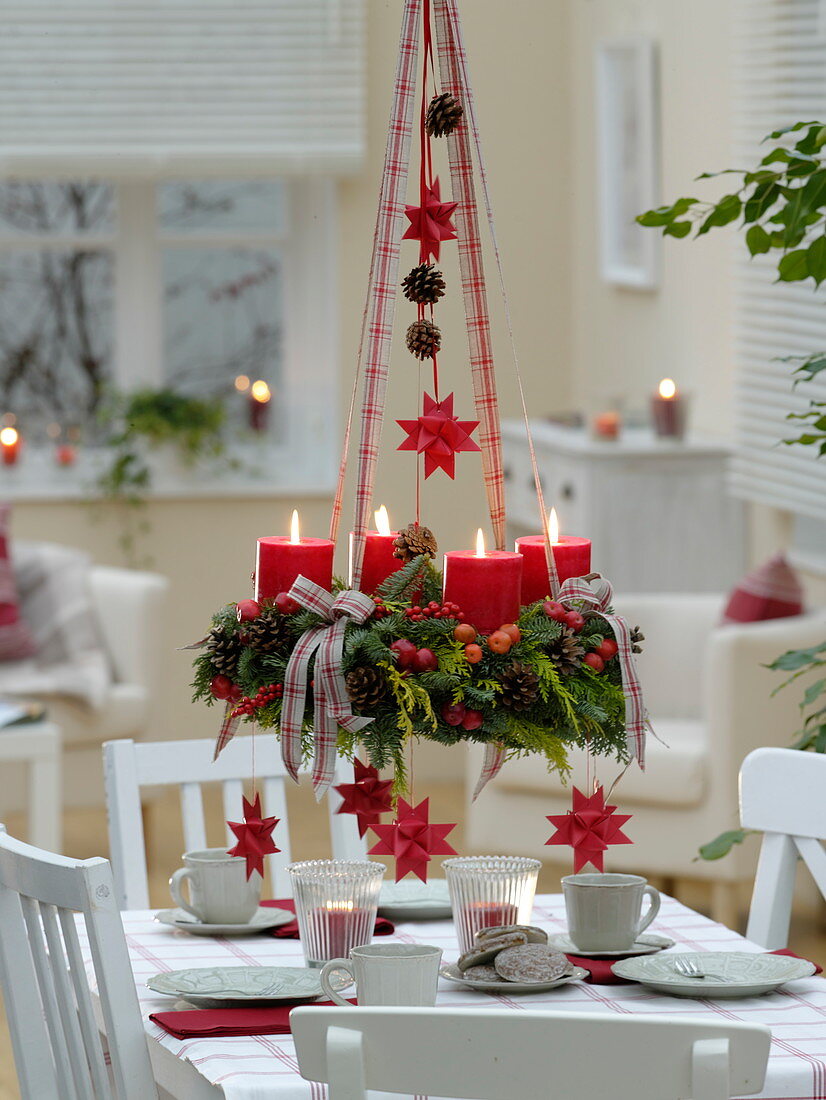 Gemischter Adventskranz mit roten Kerzen über dem Tisch aufgehängt