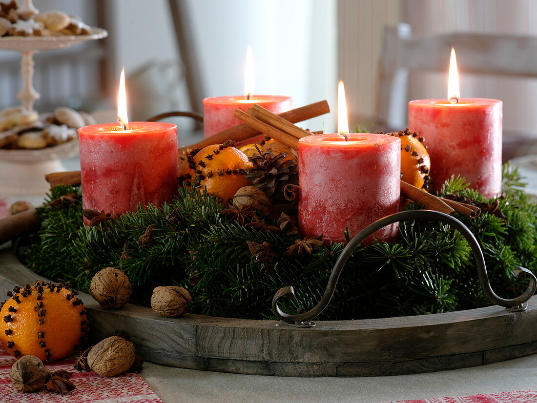 Advent wreath made of Abies (fir) with red pillar candles on wooden tray