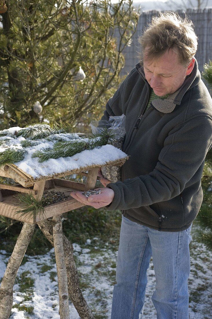 Man filling bird food into bird house