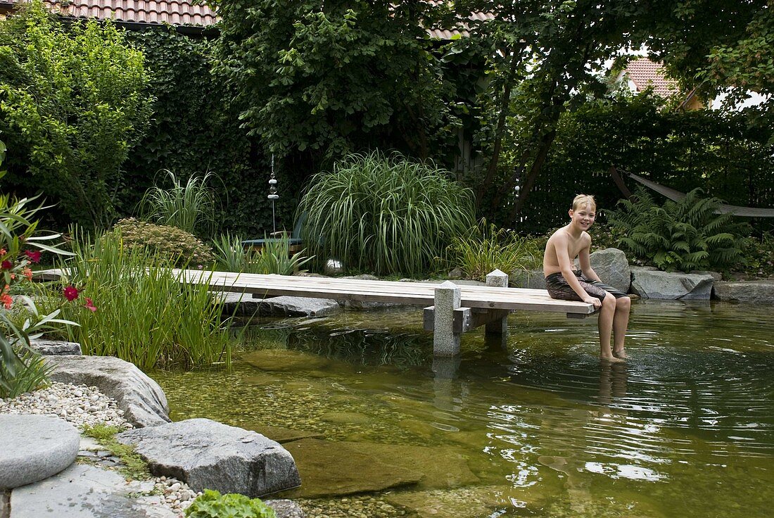 Schwimmteich mit Holzsteg eingefaßt mit Granit-Blöcken