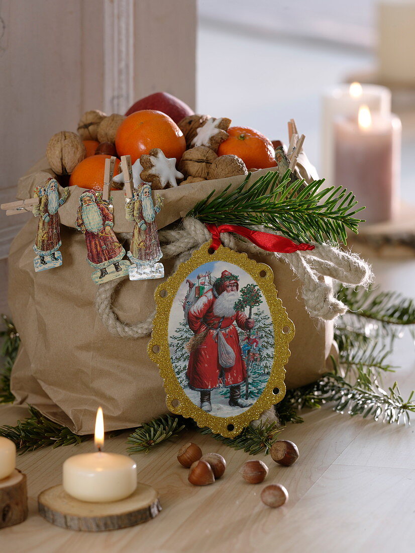 Paper bag with Father Christmas wafers, filled with mandarins (citrus), nuts