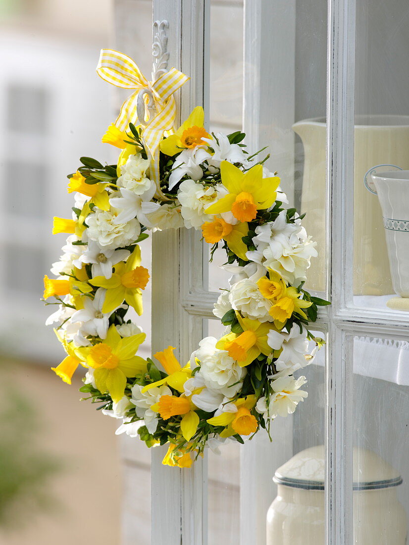 Fragrant spring wreath on the cupboard: Narcissus (daffodils), Primula