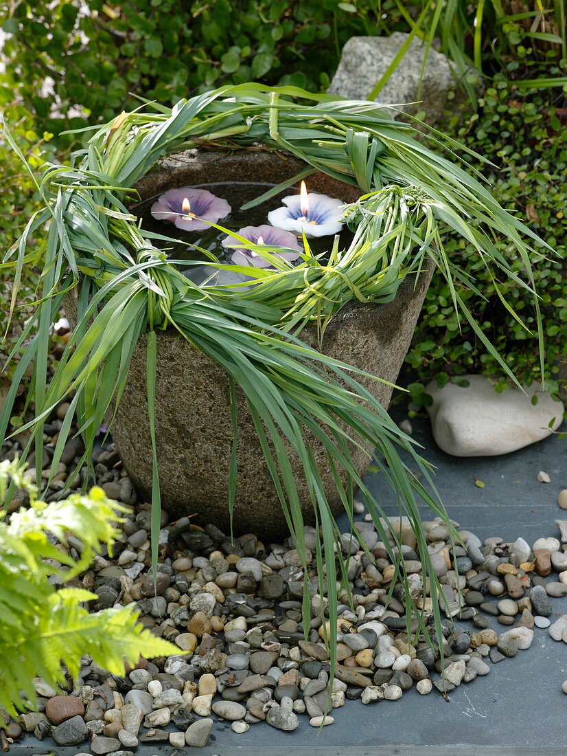 Wreath of grasses on a stone trough with floating candles