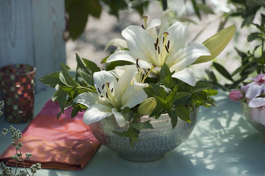 Silver bowl with white flowers of Lilium (Lily) and Mint (Mentha)