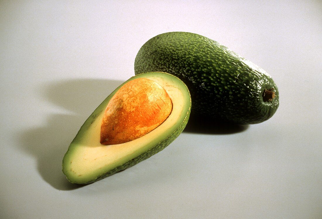 Fruchtgemüse: Eine ganze & eine halbierte Avocado mit Kern
