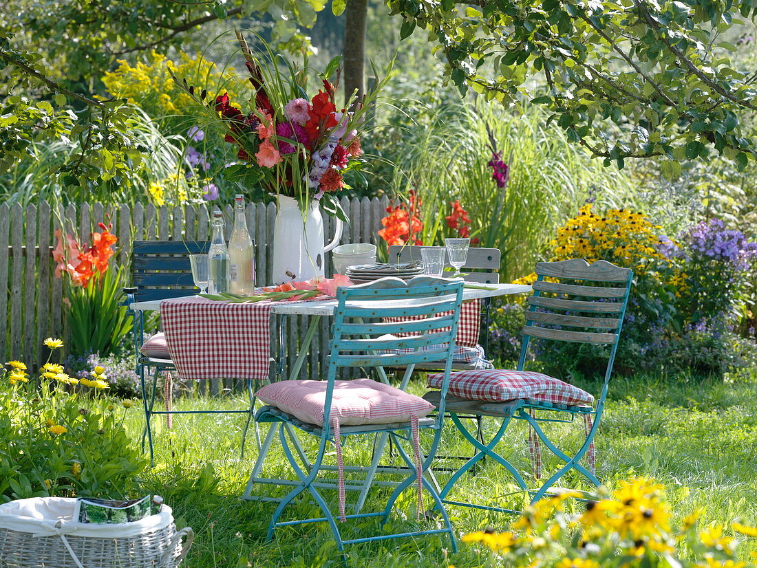 Table with gladiolus-dahlia bouquet under apple tree