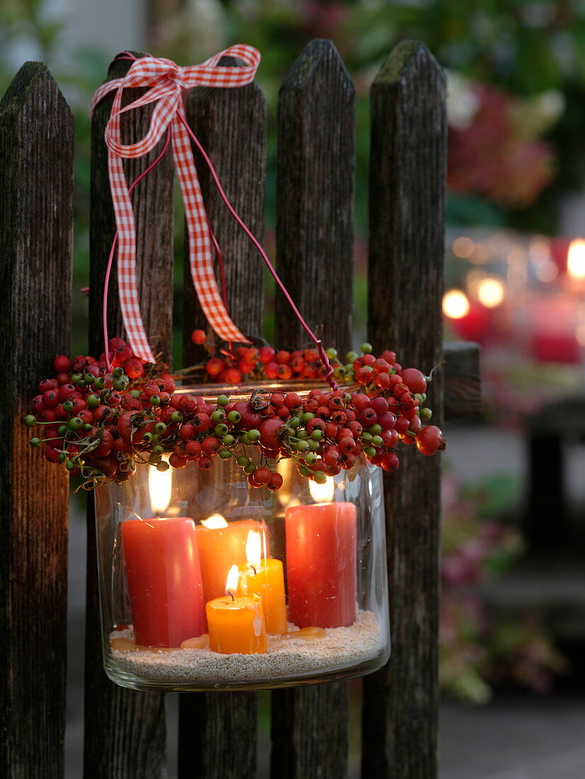 Lanterns with wreath made of roses (rosehip) tied to fence