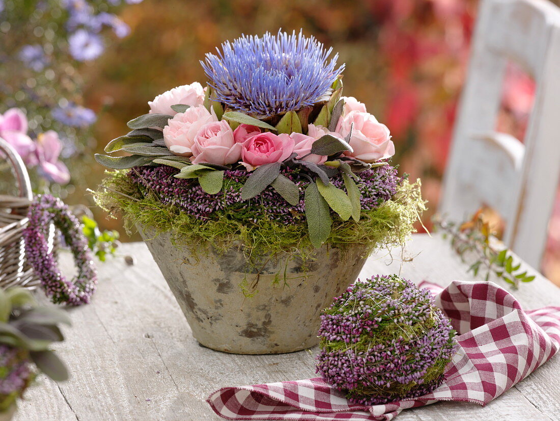 Herbstliches Gesteck im Heidekranz: Artischocke (Cynara), Rosa