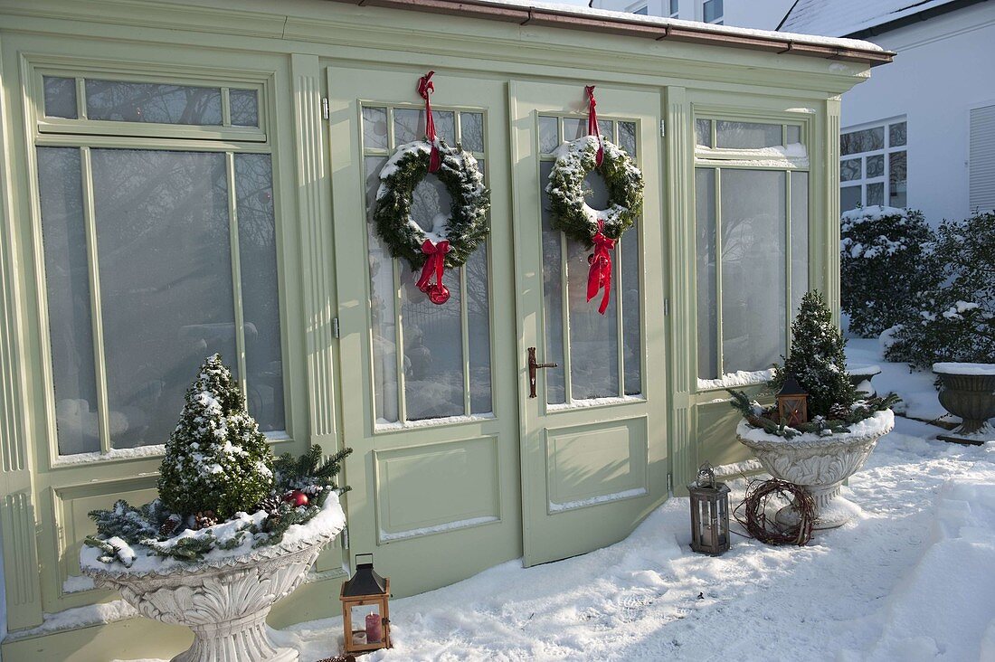 Snowy garden house decorated for Christmas with wreaths