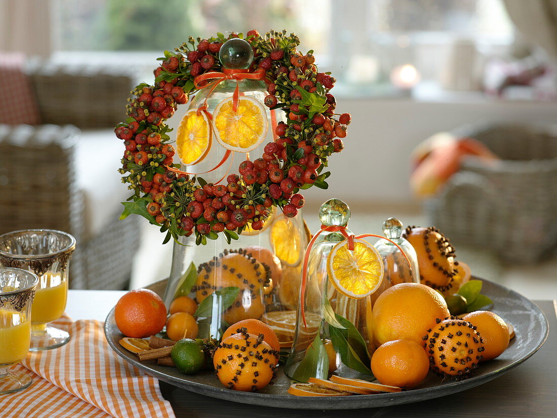 Plate with oranges, orange slices, pomander, mandarins and limes, rose hips - ivy - wreath