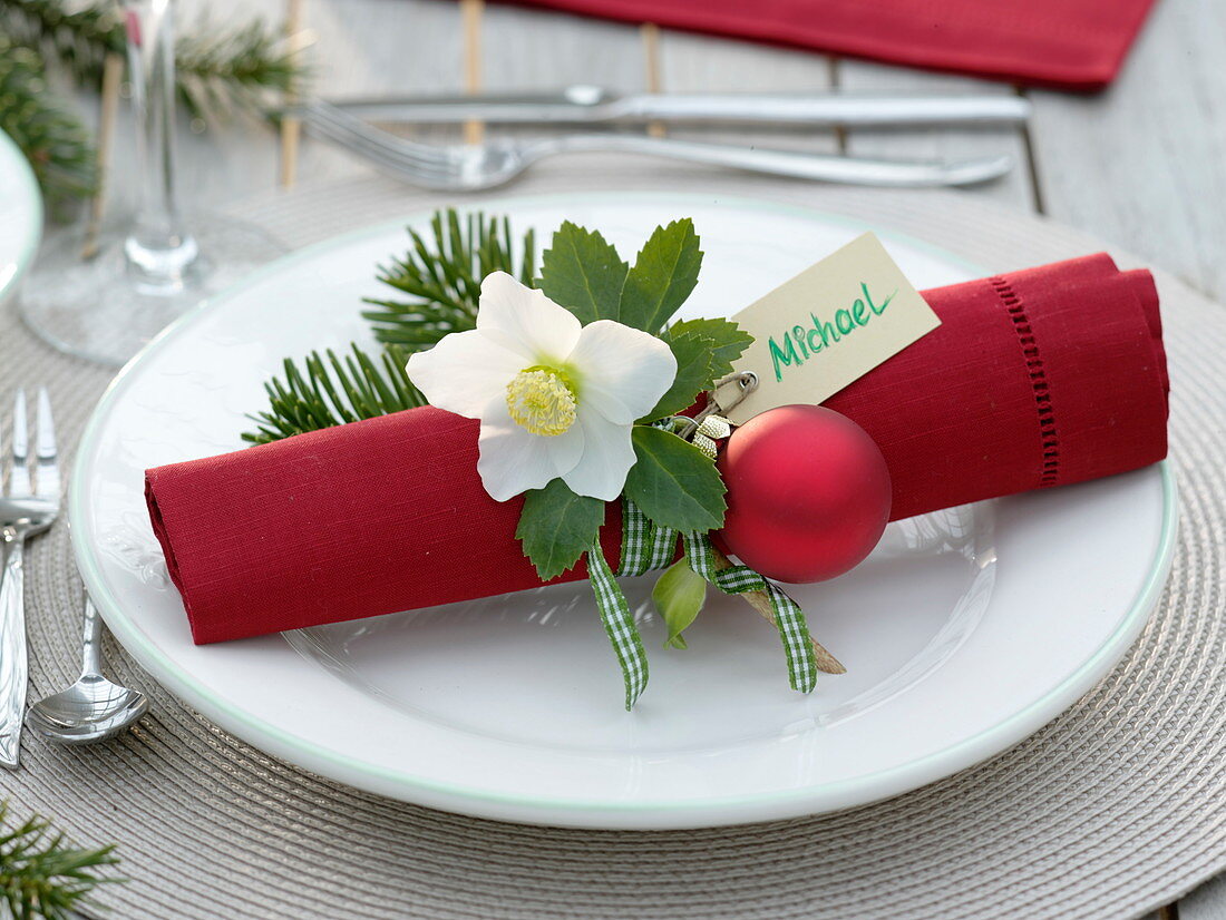 Rote Serviette weihnachtlich dekoriert mit Helleborus (Christrose)