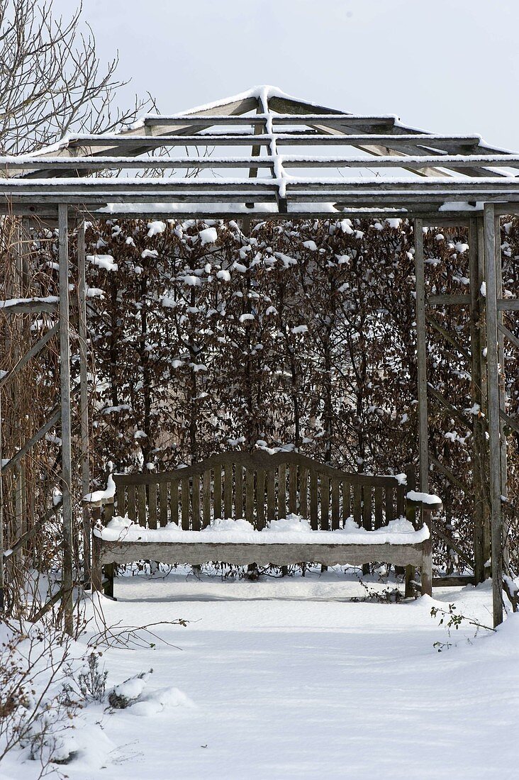 Wooden pavilion with bench in the snowy garden