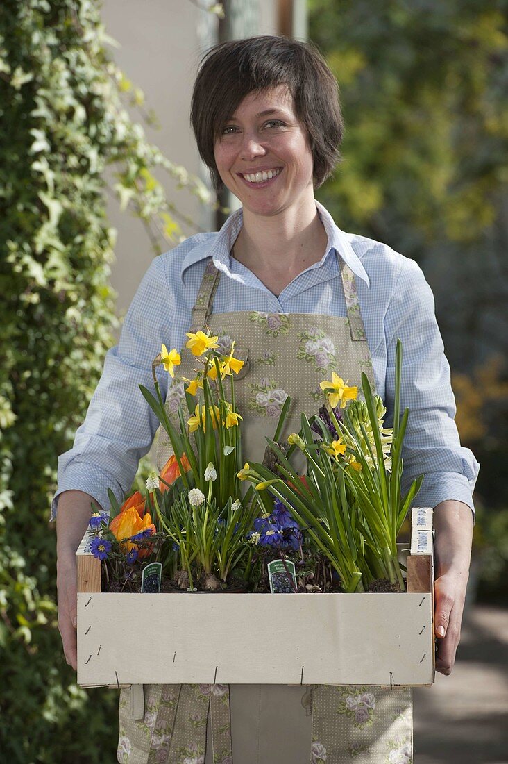 Frau mit Obstkiste voller Frühjahrsblüher