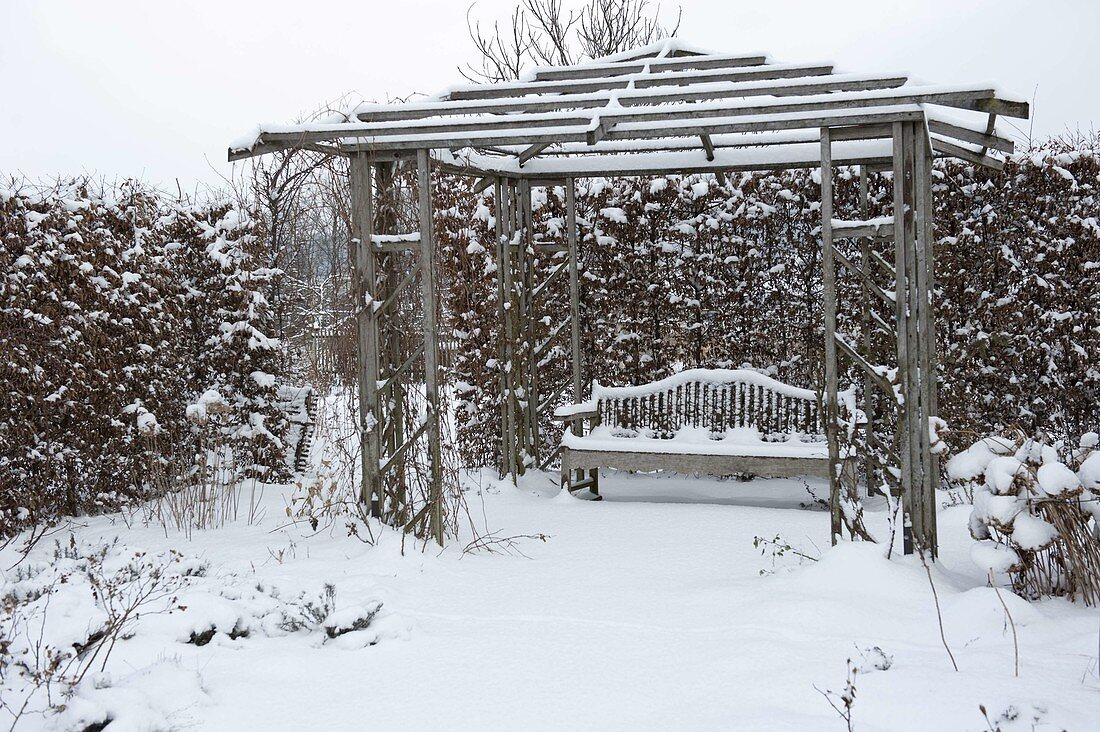 Wooden pavilion with bench in snowy garden