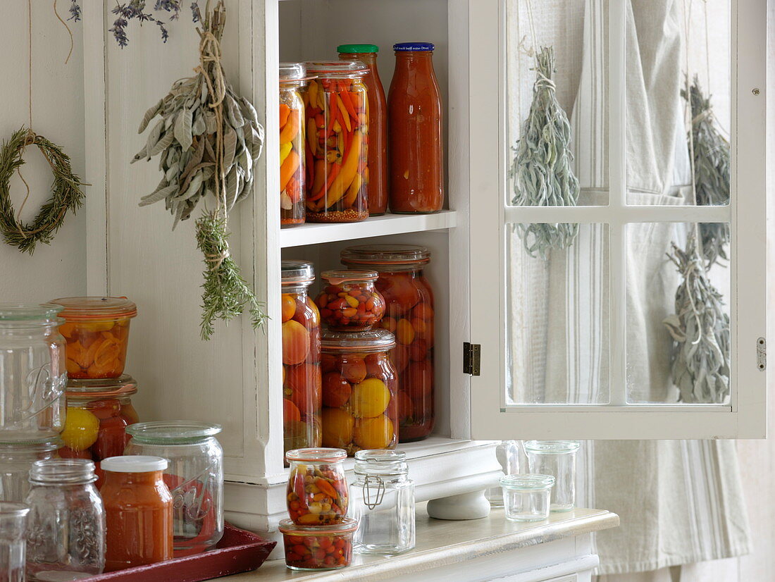 Small cupboard with preserved tomatoes in vinegar, chilli peppers and tomato sugo