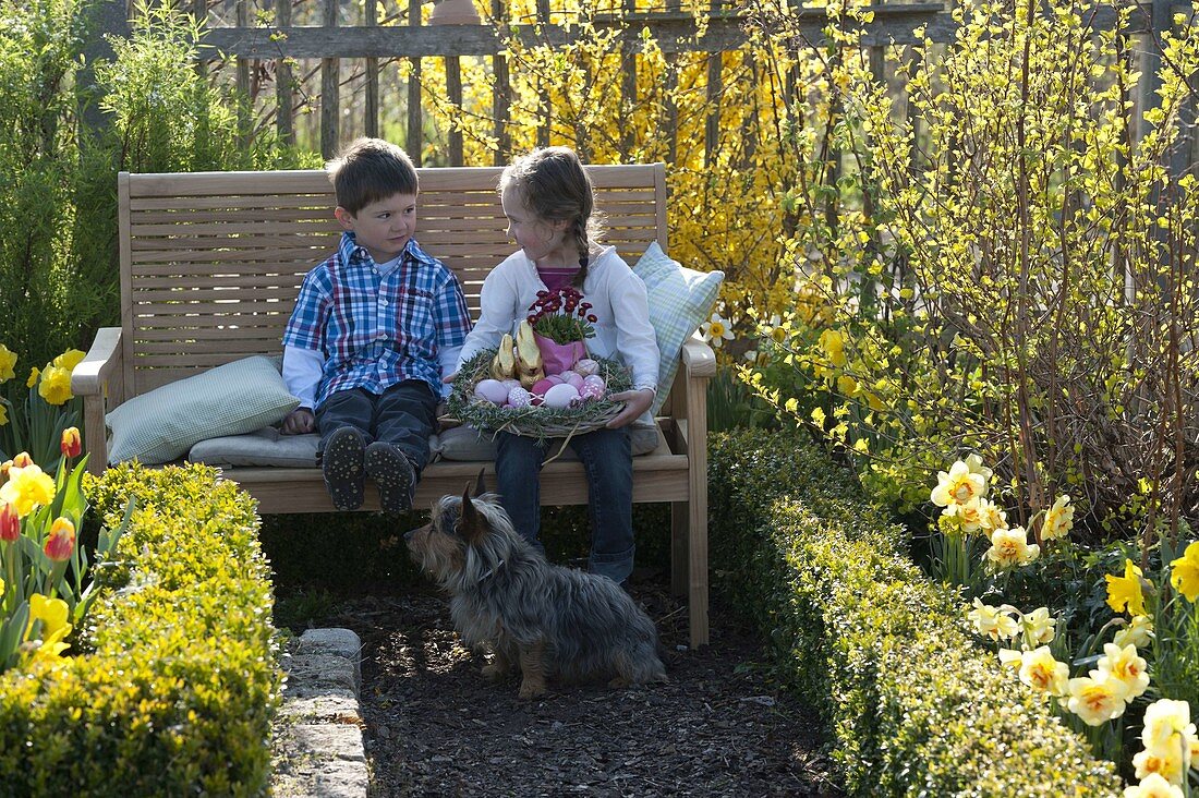 Kinder mit Osternest im Bauerngarten