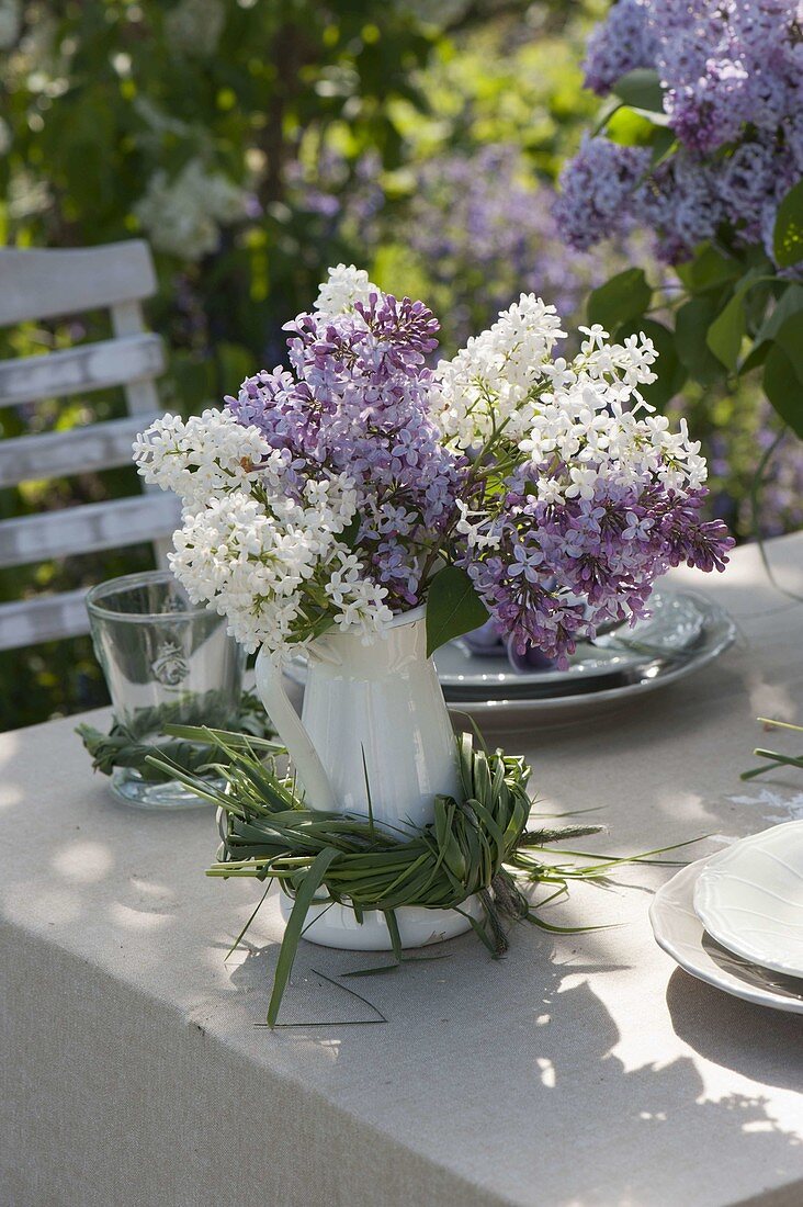 white pot with Syringa vulgaris (Lilac), wreath of grasses