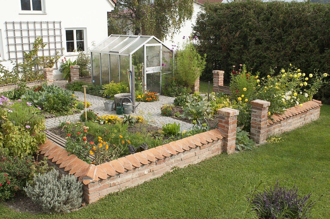 Small cottage garden with wall and greenhouse