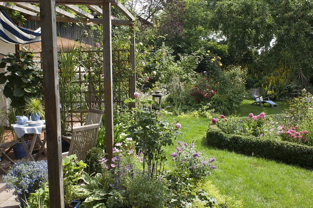 Blick von der Terrasse in den blühenden Garten mit Rosa