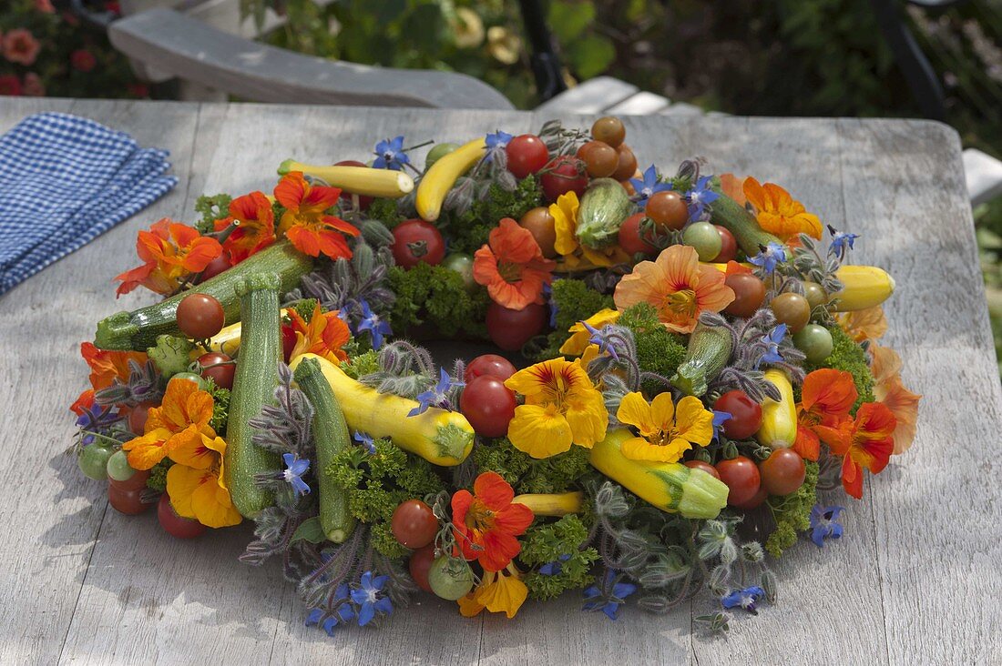 Colourful vegetable wreath with herbs and edible flowers