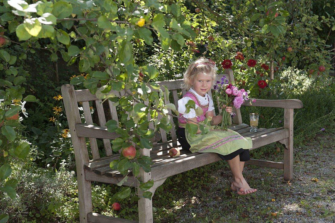 Mädchen im Dirndl mit Duftstrauß aus Rosa (Rosen) und Lathyrus odoratus