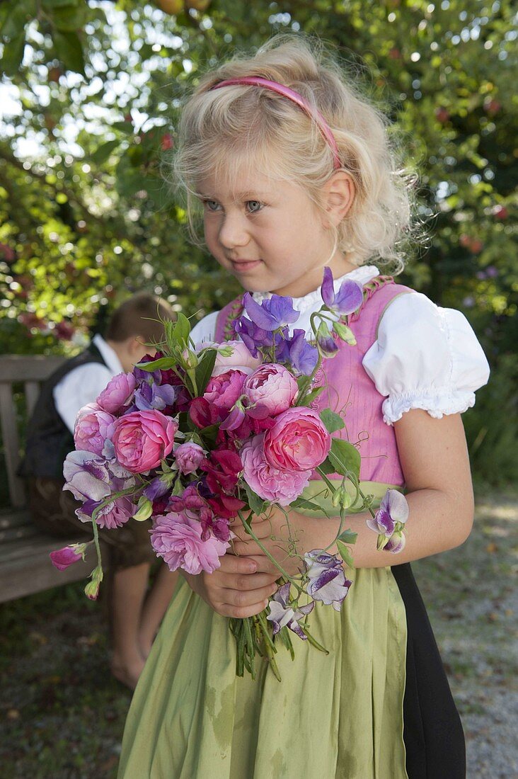 Mädchen im Dirndl mit Duftstrauß aus Rosa (Rosen) und Lathyrus odoratus