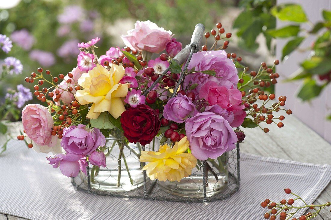 Strauß aus Rosa (Rosen) und Hagebutten in kleinem Drahtkorb