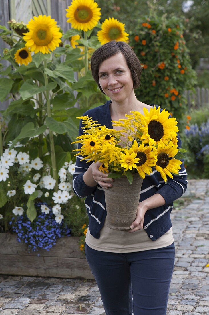 Young woman with bouquet of Helianthus decapetalus (perennial sunflowers)