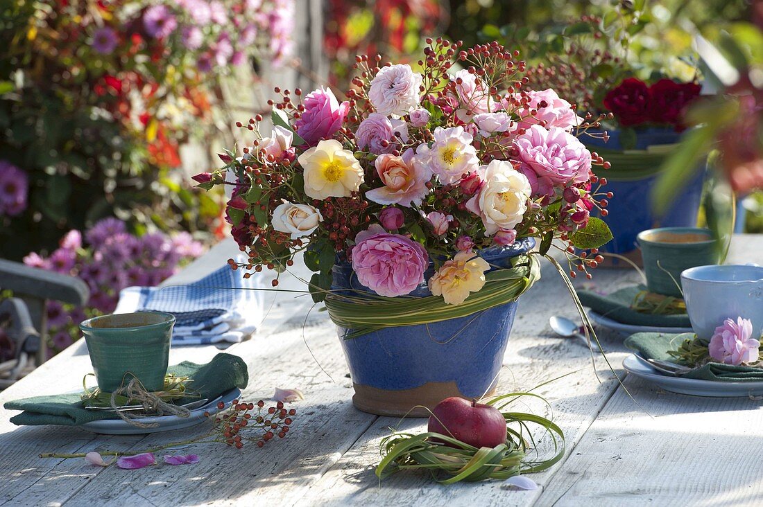 Autumn bouquet of roses and rosehips in blue vase